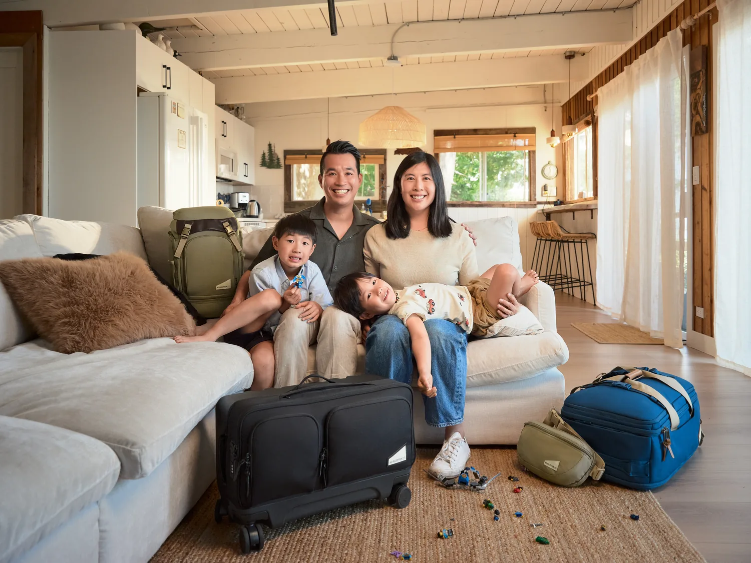 Family sitting together at home with their travel bags and Rollaway suitcase