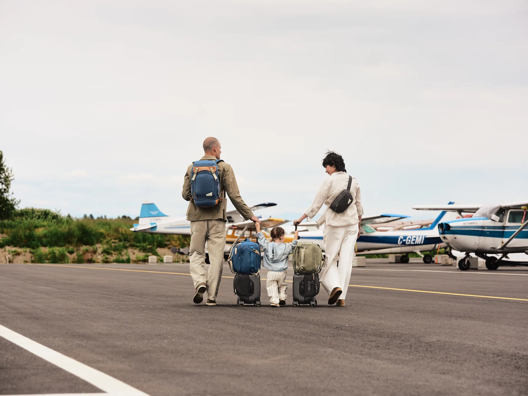 Family moving their Rollaway carry-on and other travel bags across an airfield