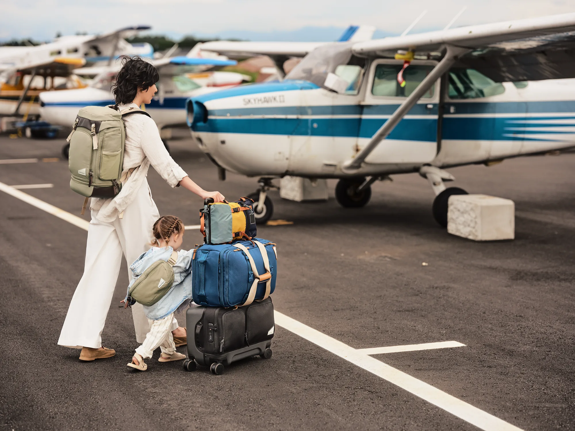 Parent and child traveling with bags stacked on a No Reception Club Rollaway carry-on